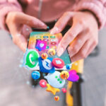 Person using a smartphone with floating social media app icons, showing social media engagement, mobile marketing, and digital communication.