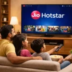 How JioHotstar Became India’s Streaming Powerhouse—A Brand Case Study 5 Indian family of four sitting on a sofa watching JioHotstar on a smart TV in a cozy living room with warm lighting.